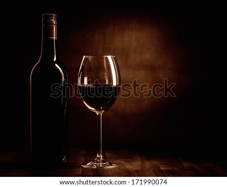The red wine bottle and full glass on the table, dark brown theme and canvas background