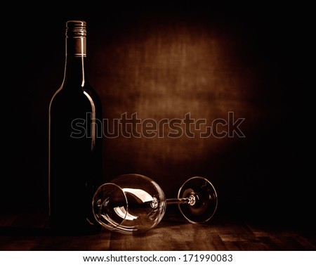 The red wine bottle and empty glass on the table, dark brown theme and canvas background
