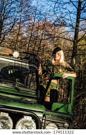 Beautiful girl on camouflage outfit and the off-road vehicle