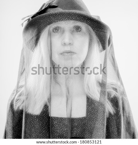 Widow, mature woman wearing black costume and veil, studio shot