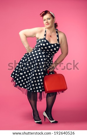 Mature pin-up woman wearing 50s style dress, pink background