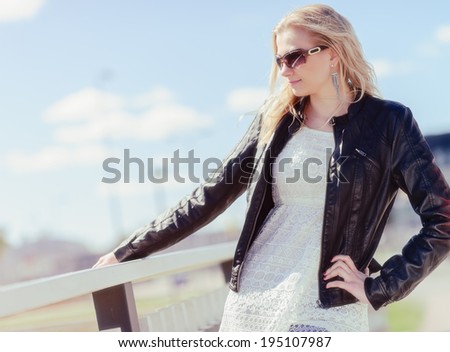 Fashionable beautiful young blond wearing a leather jacket, warm sunny day