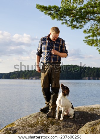 The hunter trains his English Springer Spaniel puppy on the shore