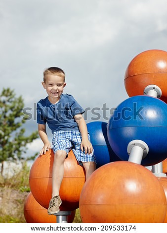 Six year old boy sits on the climbing frame