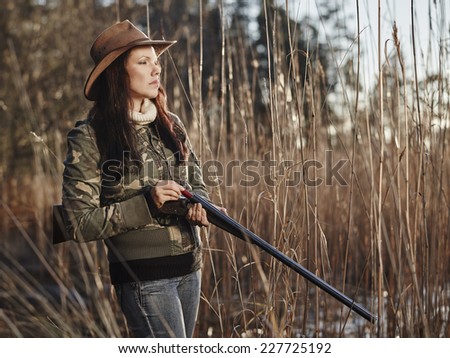 Waterfowl hunting, the female hunter loading the side by side shotgun, shore and reeds on background