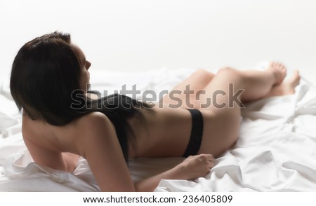 Attractive seminude woman wearing white fabric and she lying on the white bed sheets