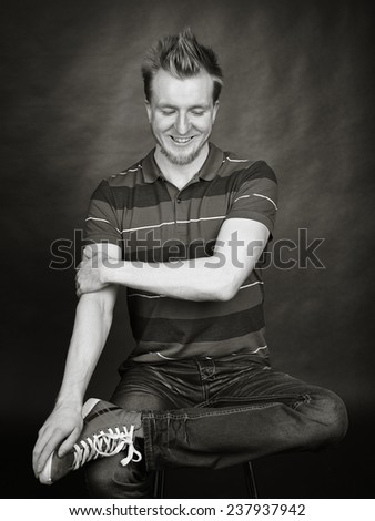 Expressive handsome young man sits in the studio - black and white image, dark background