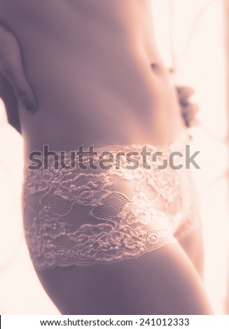 Close up, attractive young woman wearing lingerie and she stands front of the window - tinted image