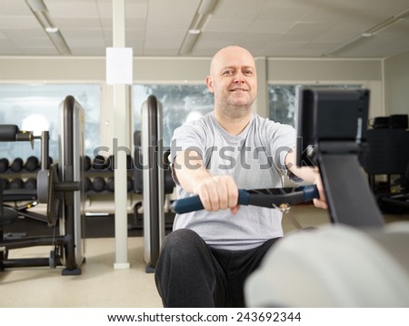 Mature man takes care of his health and he rowing in the gym