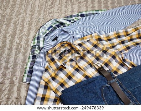 Men\'s casual patterned shirts and jeans on the bed