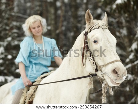 Attractive woman wearing blue dress and she riding a white horse, focus on horse eyes