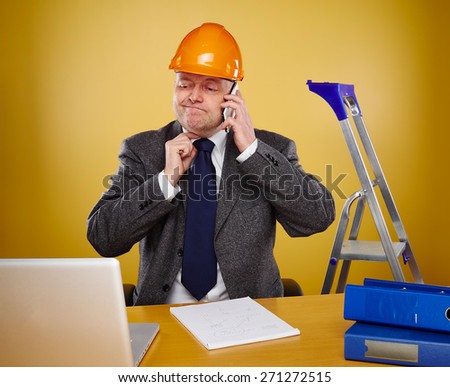 Working male engineer in office, he wearing a white shirt and tie and coat, head he wears a orange hard hat