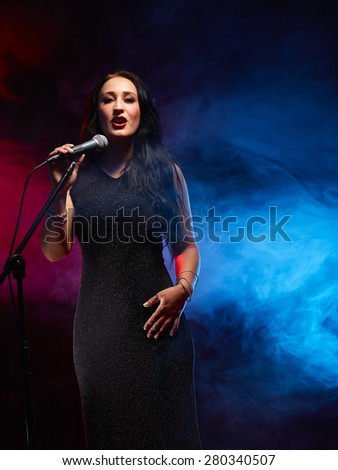 Beautiful woman sings, smoky stage on background