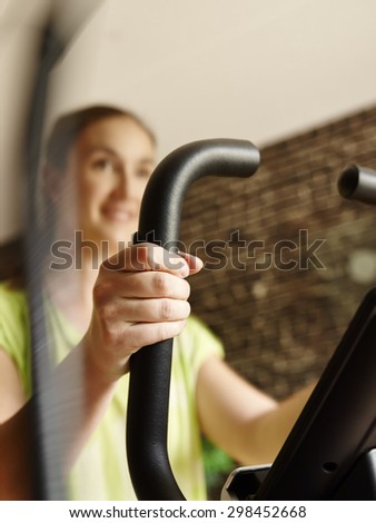 Young woman takes care of his health and she use elliptical trainer, intentional motion blur and narrow field of depth