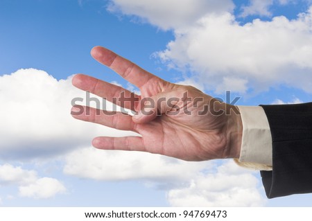Mans hand, showing four fingers, cloudy blue sky background.