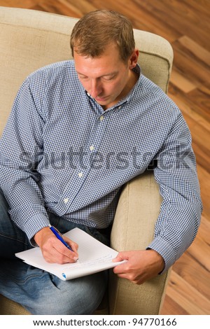 Man writing letter on the armchair.