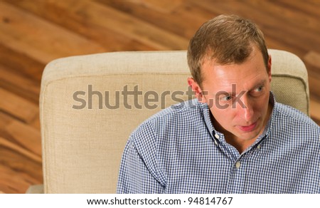 Man sitting on the armchair and looking left.