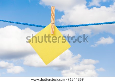Yellow note hanging in a rope with sky background.