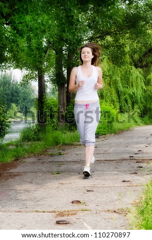 Girl  jogging along a path through a park as she takes her daily exercise to keep fit