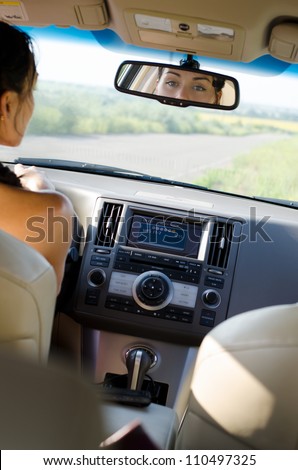 View from the back of the vehicle of a woman driver looking in her rear view mirror