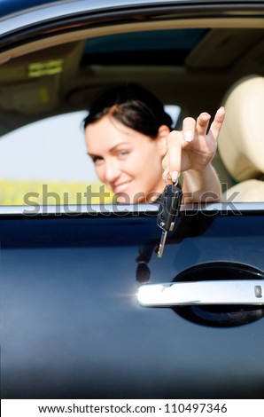 Woman handing a set of keys out of a car window with focus to the car keys