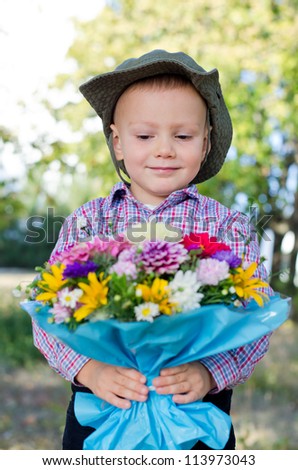 Smiling little boy presenting a bunch of flowers to his Mum on Mothers day or his Valentine sweetheart