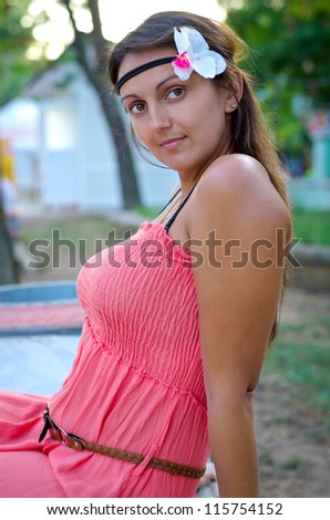Closeup of an attractive woman wearing a headband with a flower in her hair and pretty summer dress