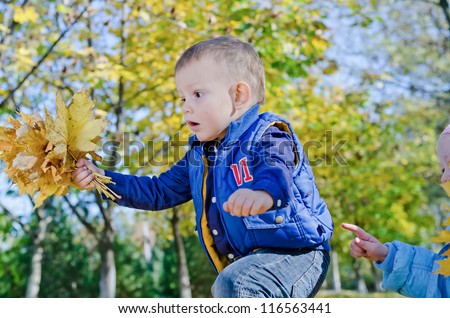 Excited little boy playing with autumn leaves with a look of awe and amazement on his face