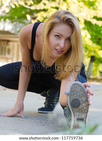 Athletic supple wman exercising bending down low on the ground with her foot extended stretching her muscles as she touches her toes