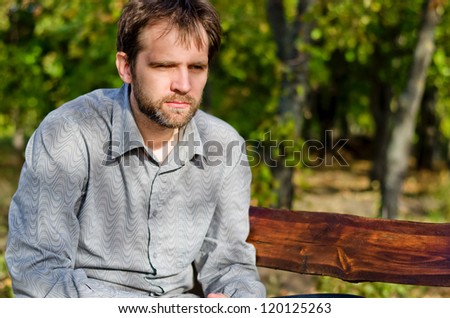 Man sitting outdoors on a wooden bench thinking deeply about his chess game as he considers his next move