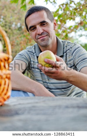 Man looking an apple at the park
