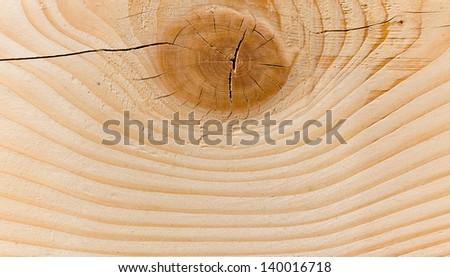 Wood background texture and pattern with concentric growth rings, a knot and a large crack on a plank of natural pine