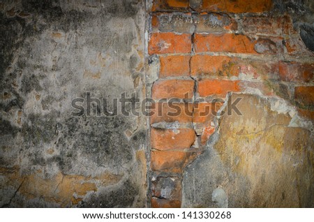 Background texture of old decaying walls with mold in one and falling concrete pieces on the other showing the red clay bricks under