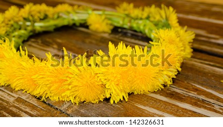 Floral garland made of yellow flowers laying on top of an old wooden table