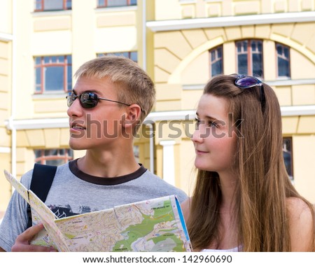 Young man and woman sightseeing with a map in front of a hsitorical building facade as they enjoy their summer holiday