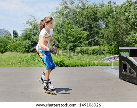 Pretty young teenage girl roller skating in her roller blades at a skate park in the summer sunshine