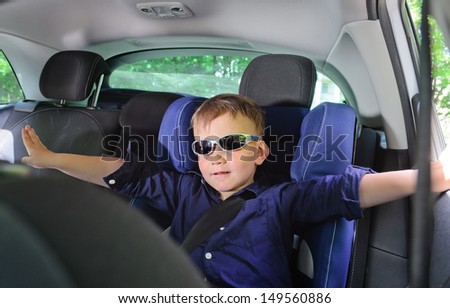 Little boy sitting in his car seat wearing sunglasses