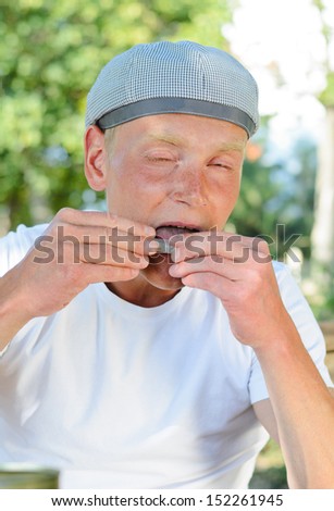 Man making his own cigarette licking the edge of the rollings, or paper in which he has rolled the loose tobacco, in order to seal it