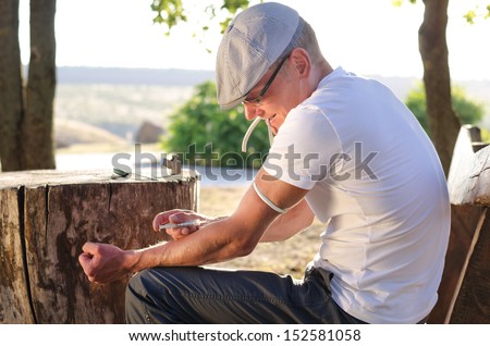 Caucasian addicted man injecting his tied arm intravenously with a dose of soluble heroin in the park