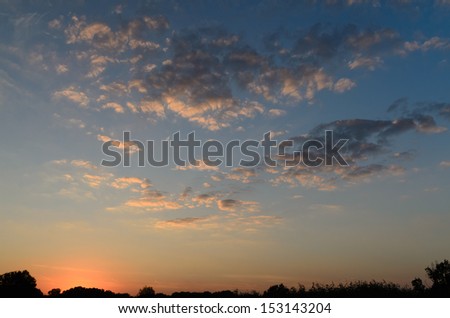 Dramatic scenic nature image with horizon line under a cloudy sky at sunset