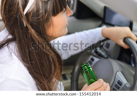 Up view of the hand of a woman drinking while driving gripping a green bottle bear