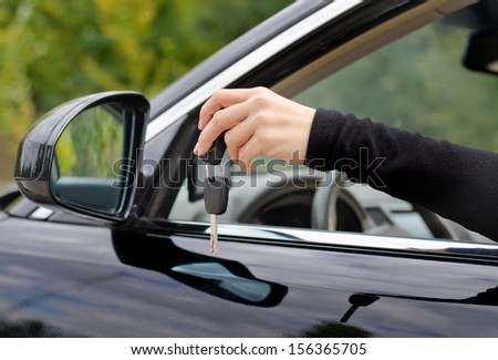 Black car key holding by the human hand in a close up shot