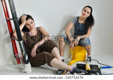 Exhausted women taking a break from renovating relaxing on the floor surrounded by a variety of tools and equipment