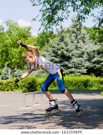Teenage girl roller blading in a skate park passing the camera at speed with her hands raised in the air