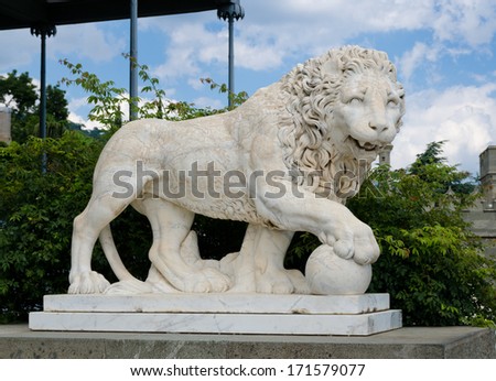 Side view of a naturalistic stone carved lion statue outside a historical castle or manor house