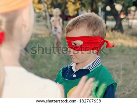 Young boy playing at a kids birthday party wearing a super hero mask as he chats to his young friends
