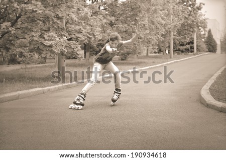 Beautiful young teenage girl roller skating cornering at speed on a tarred rural road with her ponytail flying out behind her