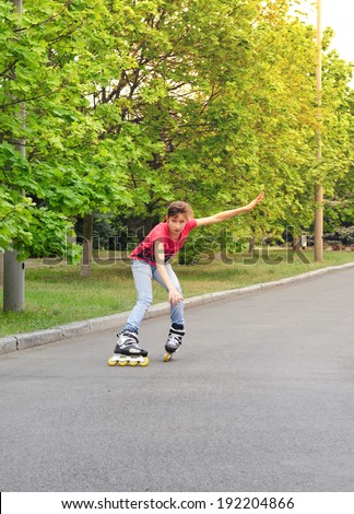 Attractive teenage girl roller skating on roller blades on a tarred rural road rounding a bend at speed with her arms flying