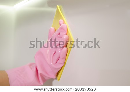 Gloved hand wiping a white surface with a cloth in a cleanliness, hygiene and household chores concept