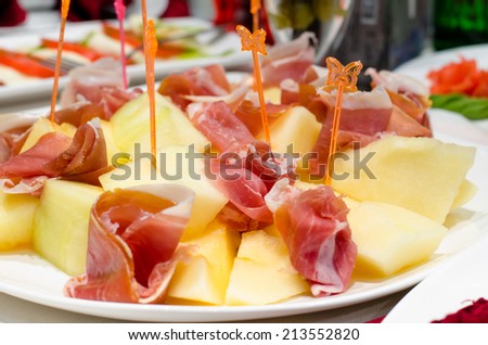 Serving of delicious smoked ham and cheese appetizers displayed on a plate on a buffet at a party or reception